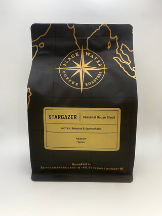 Black coffee bag with gold accents featuring 'Black Water Coffee Roasters' on a white background with a Stargazer (Seasonal House Blend) label